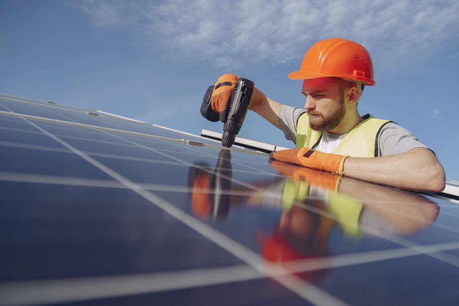 Professional solar panel installer working on a residential roof